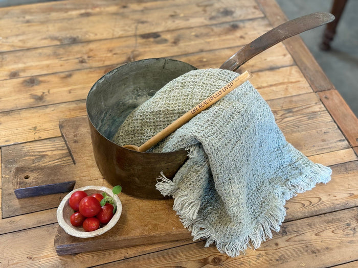 Aged copper pot with patina finish, wooden spoon and folded cloth inside