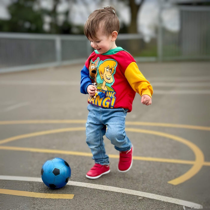 Toddler wearing red mesh trainers playing football