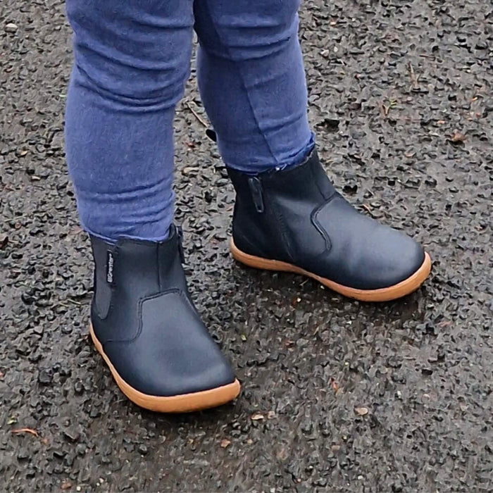 Toddler in car park wearing navy barefoot style boots