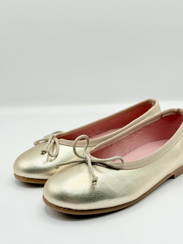 Gold ballet flats on a white background