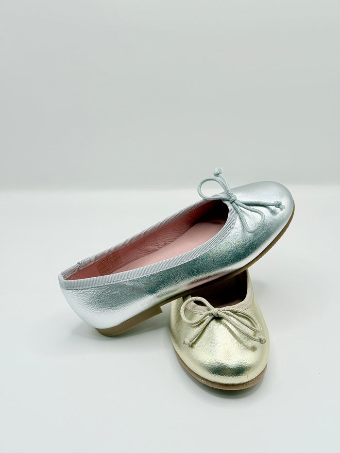 Pair of metallic silver shoes with bow details on a light gray background