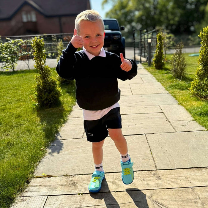 Child giving thumbs up on a wooden pathway