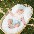 Baby in a Moses basket on grass with 'Granlei' branding.