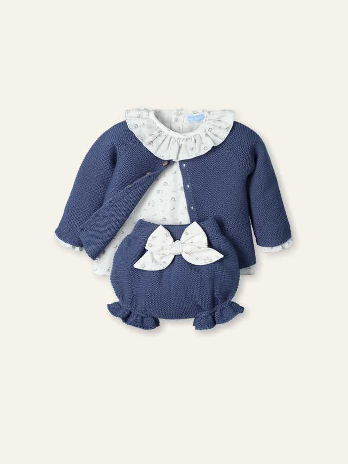 Children's blue sweater set with white ruffled collar and bow on a light beige background
