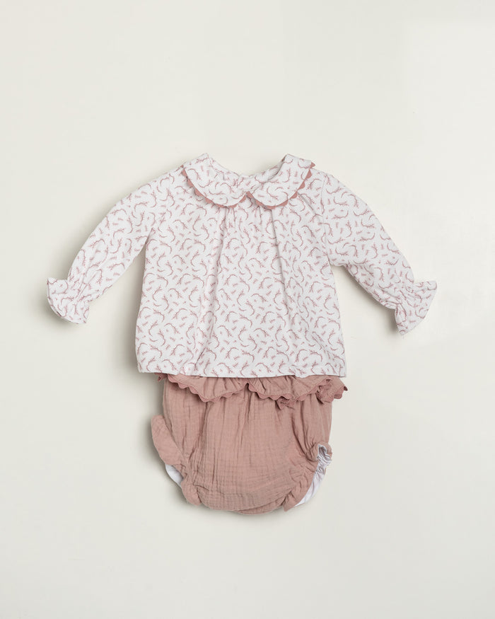 Baby outfit with floral top and pink bloomers on a light beige background