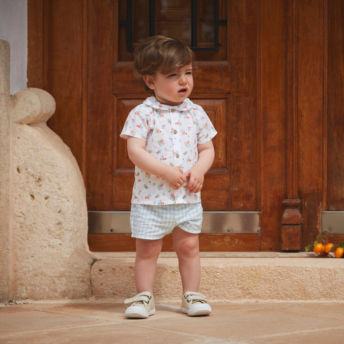 Child standing in a room with wooden doors and stone wall.