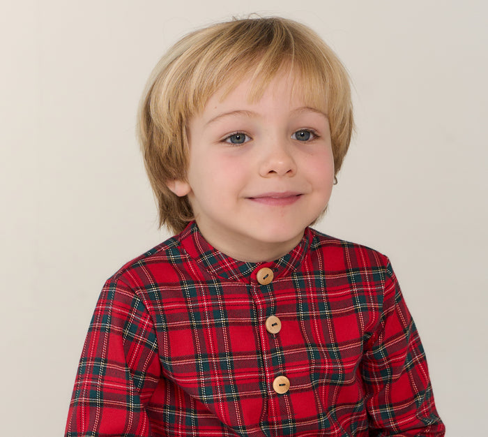 Child wearing a red plaid shirt with a plain background