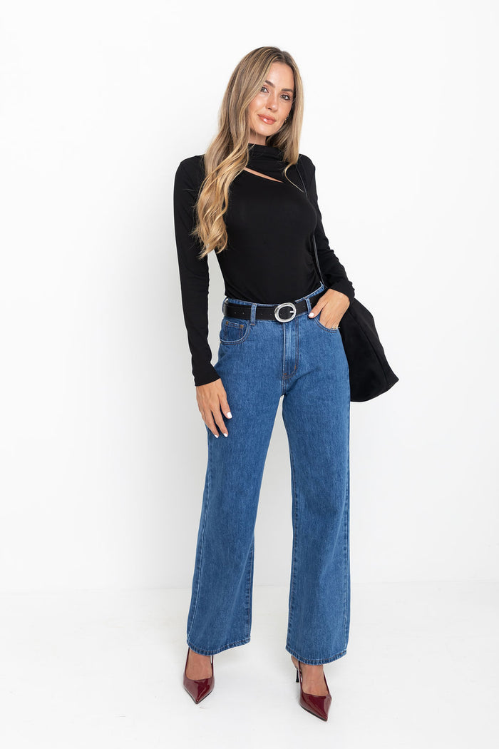 Woman wearing Carolyn black long sleeve top with cutout neckline, styled with blue wide-leg jeans, black belt, black shoulder bag, and burgundy heels
