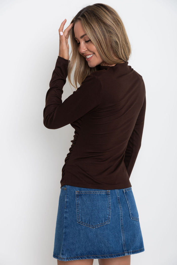 Carolyn long sleeve top in chocolate brown, fitted top with asymmetric cutout neckline, styled with a denim skirt