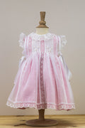 Pink lace dress on a mannequin against a plain background