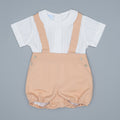 Baby romper with beige overalls and white shirt on a gray background