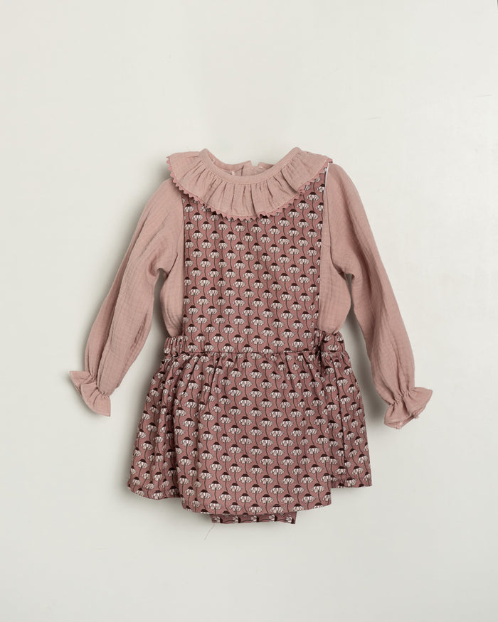 Pink patterned romper with long-sleeve top on a light beige background