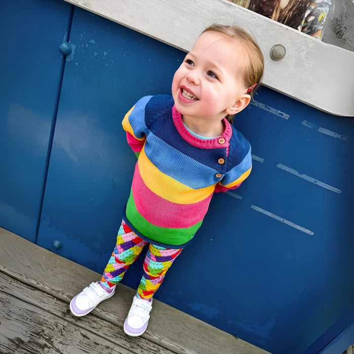 Toddler posing in Purple Barefoot Trainer leaning on blue wall