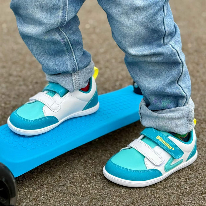 Toddler on scooter in park wearing teal trainers close up shot