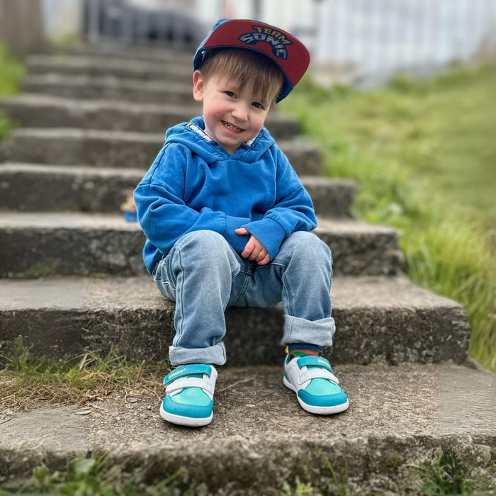 Toddler siting on steps wearing teal trainers