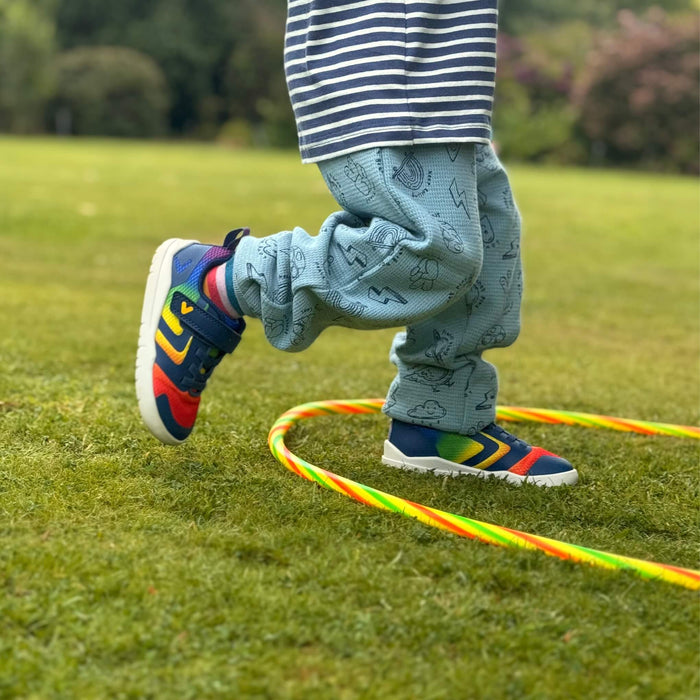 Kid playing in park in rainbow coloured trainers