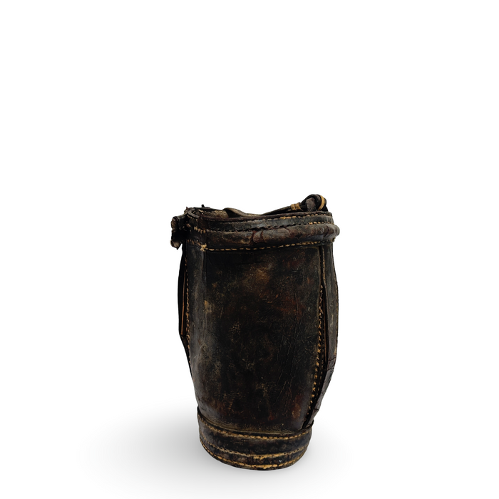 Antique metal water bucket, side view with rope handle and worn leather trim