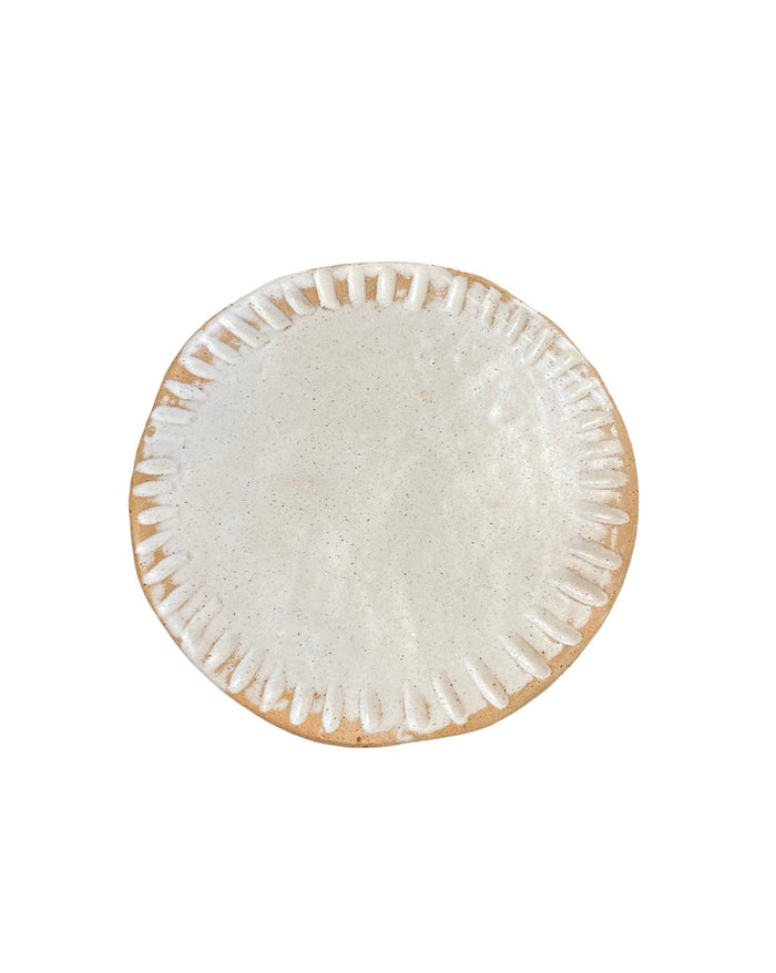 Round cream ceramic plate with textured rim and speckled center