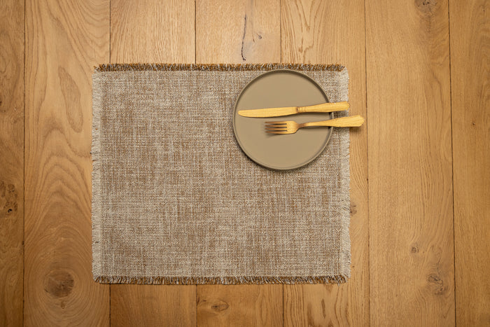 Gray square jacquard placemat with fringe border, set with plate and fork.