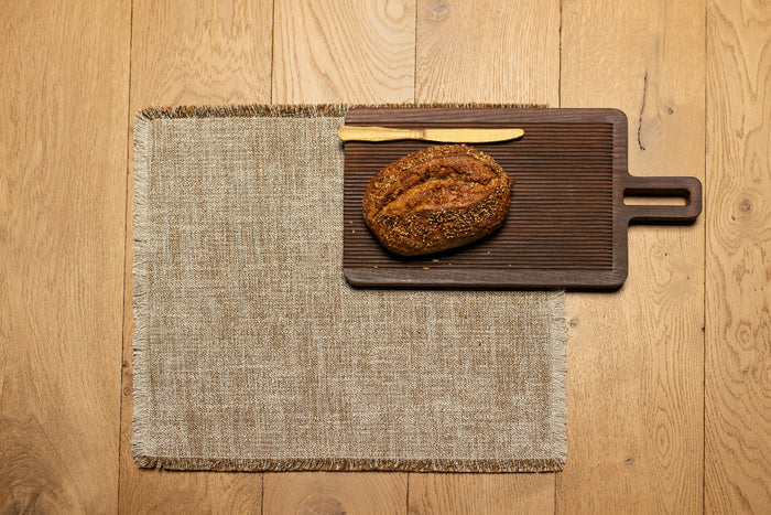 Jacquard placemat in gray with frayed woven edges, flat square.