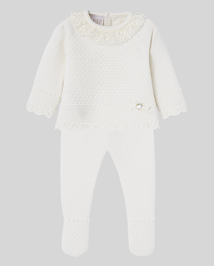White baby set with lace details on a light gray background