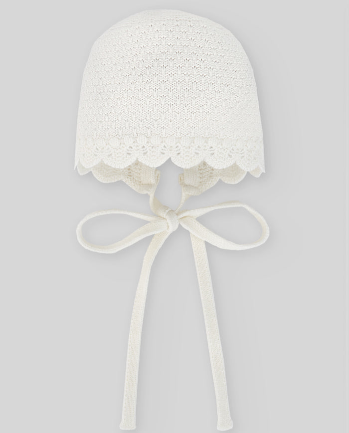 White lace bonnet with a bow on a gray background