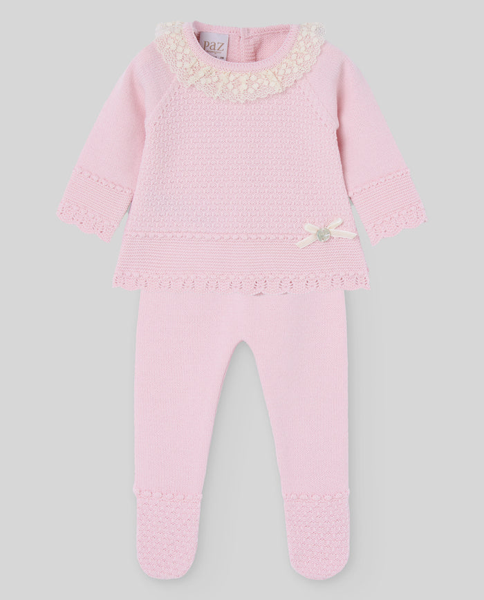 Pink baby outfit with lace details on a gray background