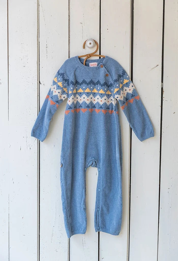 Blue knitted baby romper with a pattern on a wooden background