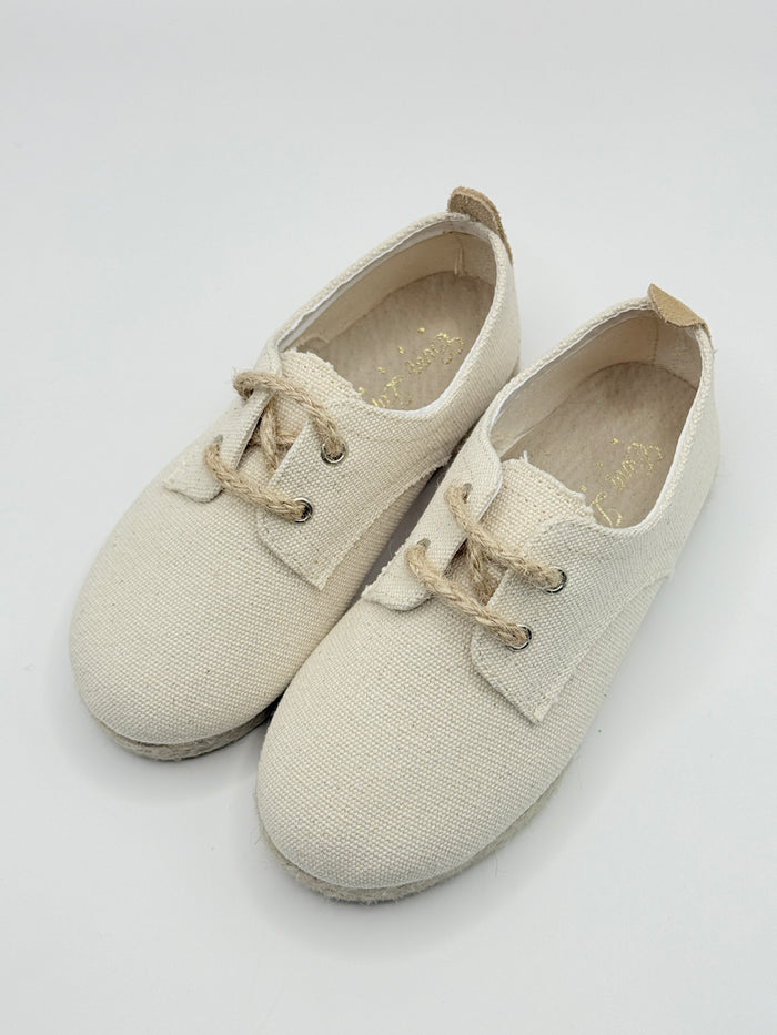 Pair of beige canvas shoes on a light gray background