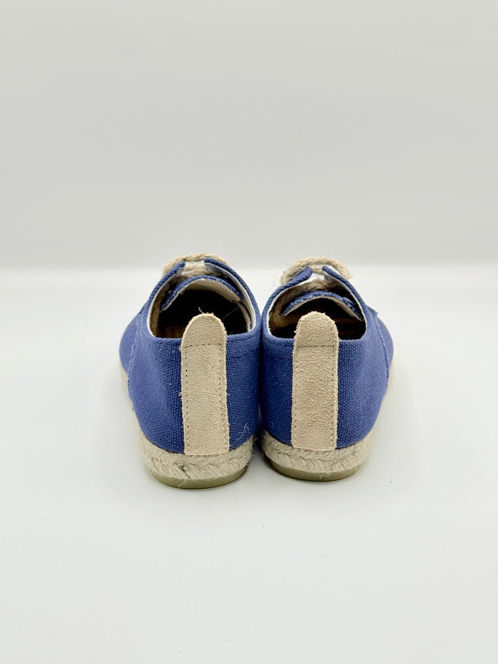 Pair of blue shoes with beige soles on a white background