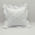 White decorative pillow with ruffled edges on a light gray background