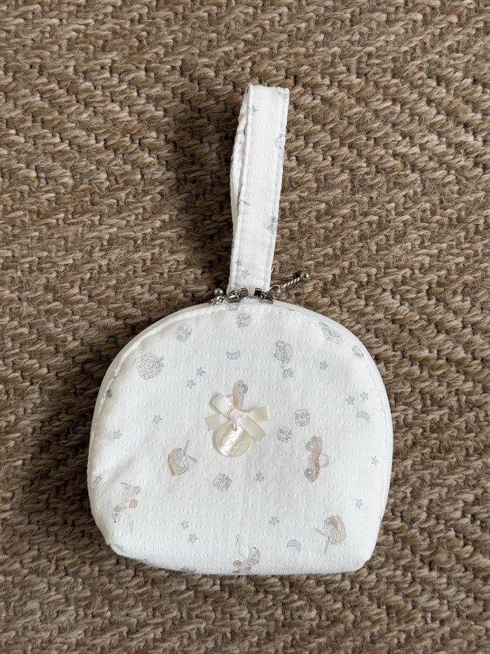 Small round white fabric pouch with a floral pattern on a brown textured background