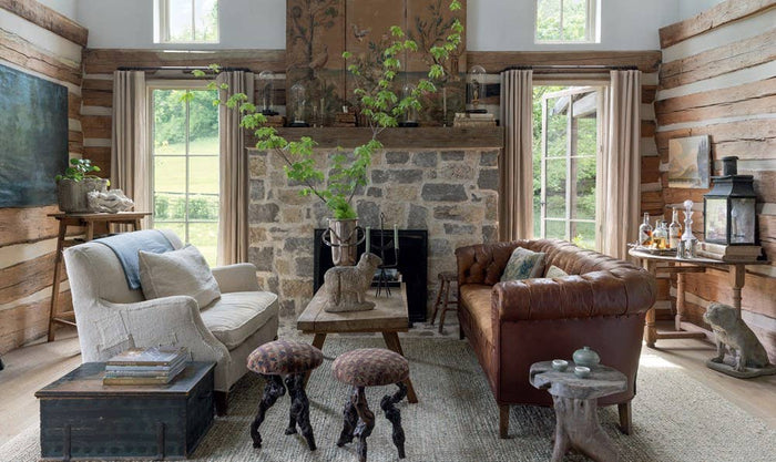 Patina Homes & Gardens book page: living room with leather sofa, stools, and stone fireplace