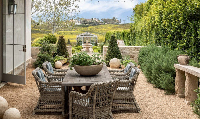 Patina Homes & Gardens book page: outdoor patio dining table with wicker chairs and hedges