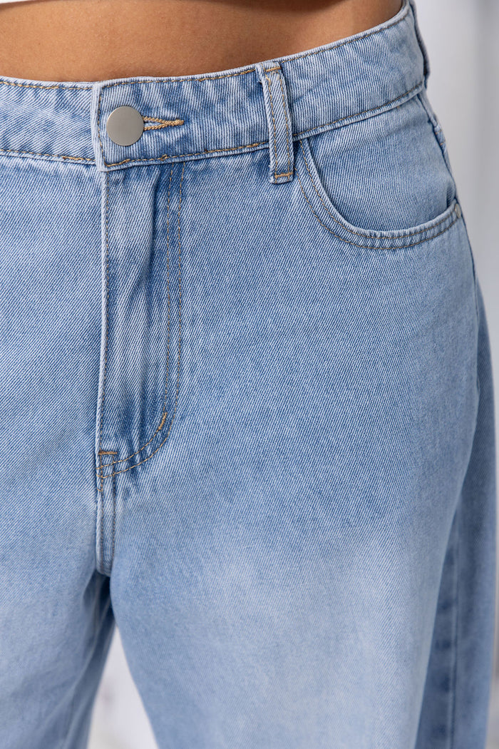 Woman wearing light-wash wide-leg jeans with a white crop top, on a white background.