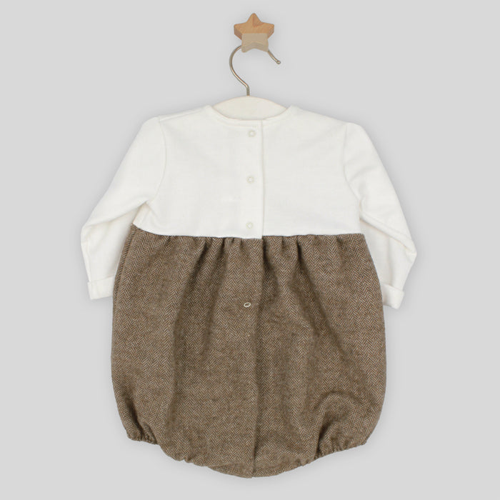 Baby romper with white top and brown bottom on a hanger against a light gray background