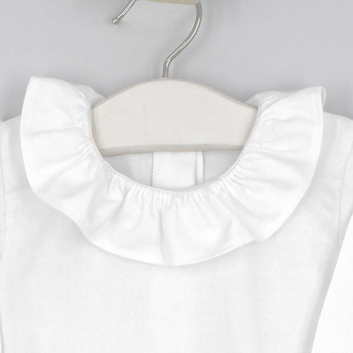 White blouse with a ruffled collar on a hanger against a light gray background