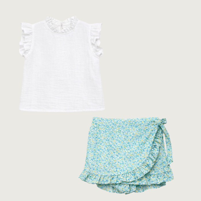 White top with ruffled sleeves and floral shorts on a light gray background