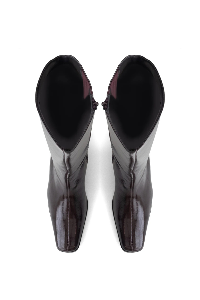 A pair of glossy dark brown leather boots with a pointed toe and high black lining, shown from a top-down view on a white background.