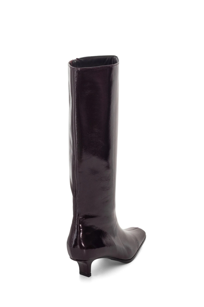 A single knee-high boot in a glossy dark plum patent leather, shown from a rear three-quarter view against a plain white background.