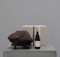 Potpourri set with dark stone on stand, dropper bottle, and beige gift box.