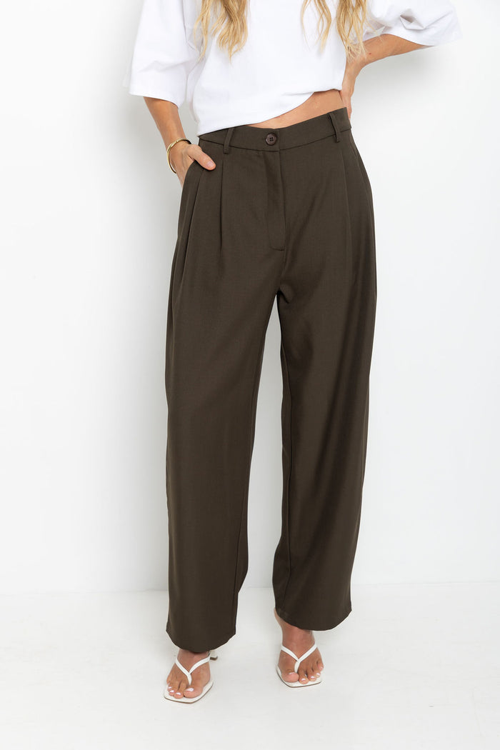 Xavier pants in dark olive brown – high-waisted, wide-leg trousers with pleated front, worn with a white cropped tee and thong sandals