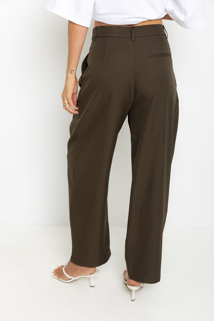 Xavier pants in dark olive brown – high-waisted, wide-leg trousers with pleated front, worn with a white cropped tee and thong sandals