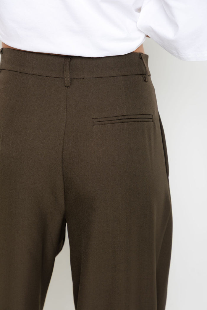 Xavier pants in dark olive brown – high-waisted, wide-leg trousers with pleated front, worn with a white cropped tee and thong sandals